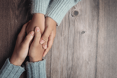 two-people-holding-hands-together-with-love-warmth-wooden-table